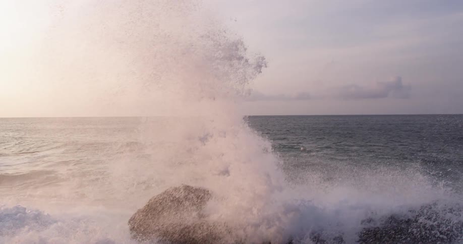 Ocean waves crash against big rock