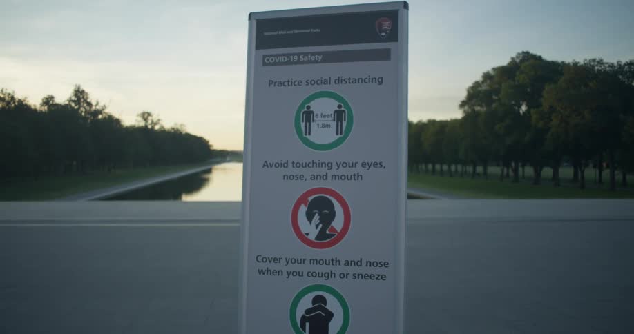 A sign warning about viruses sits on the pavement at the national mall