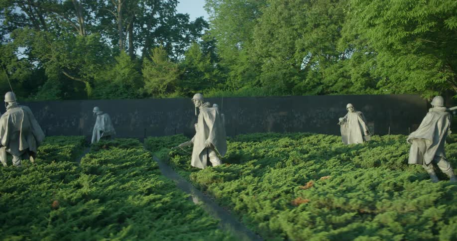 Statues of soldiers stand in bushes at a Korean war memorial