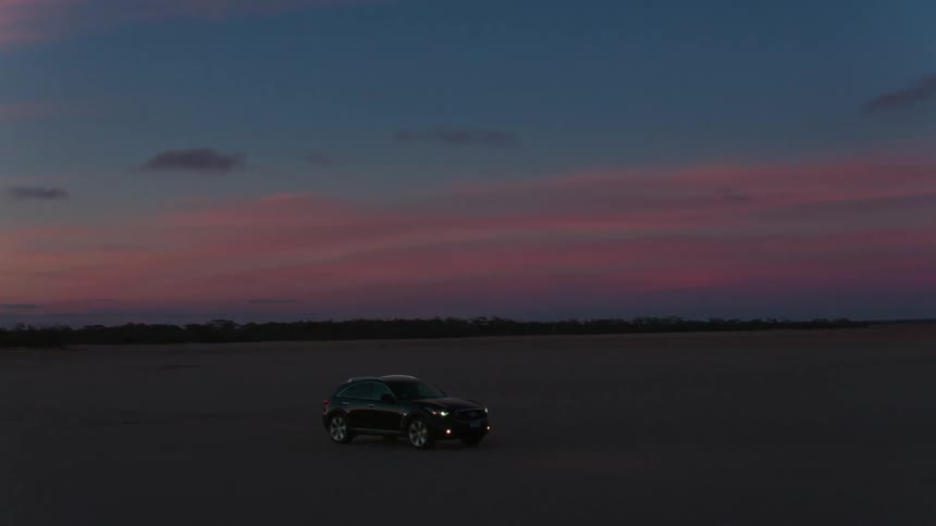 Vehicle drives on the dirt road in the desert at dusk