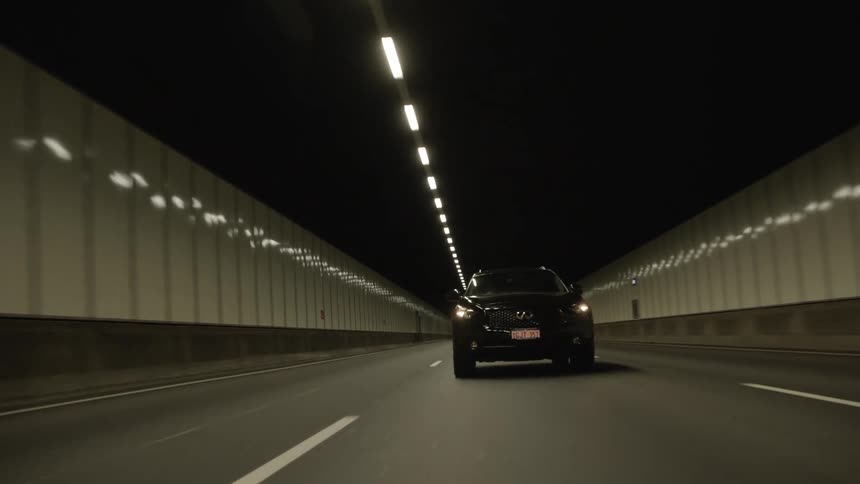 A car drives through a long lighted tunnel