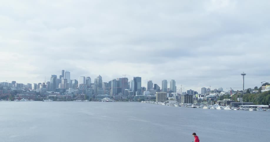 A man runs along the coast with the city skyline in the background