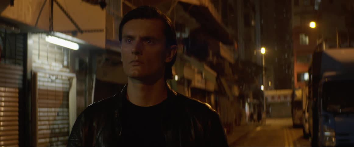 A man walks down a street at night