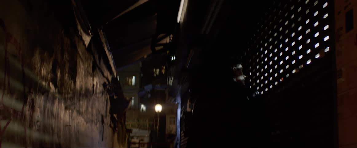 Man walks between the buildings and looks through the barred window
