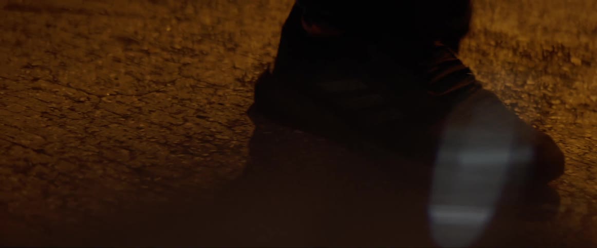 Feet of a person shuffling on the street at night
