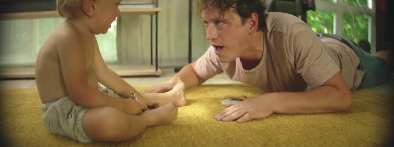 Father laying on the floor playing with his son