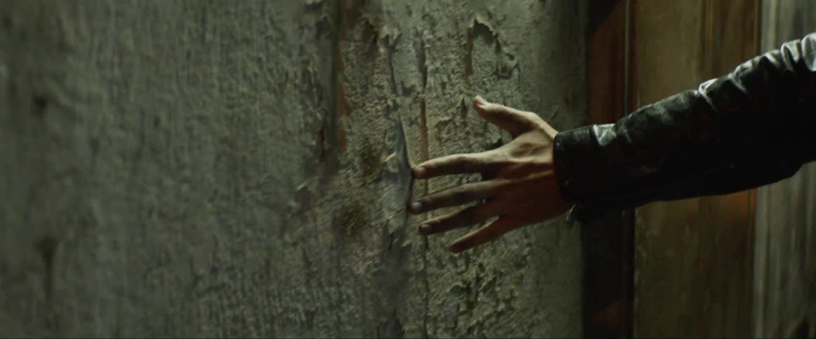 Man walks and runs his hand along a wall
