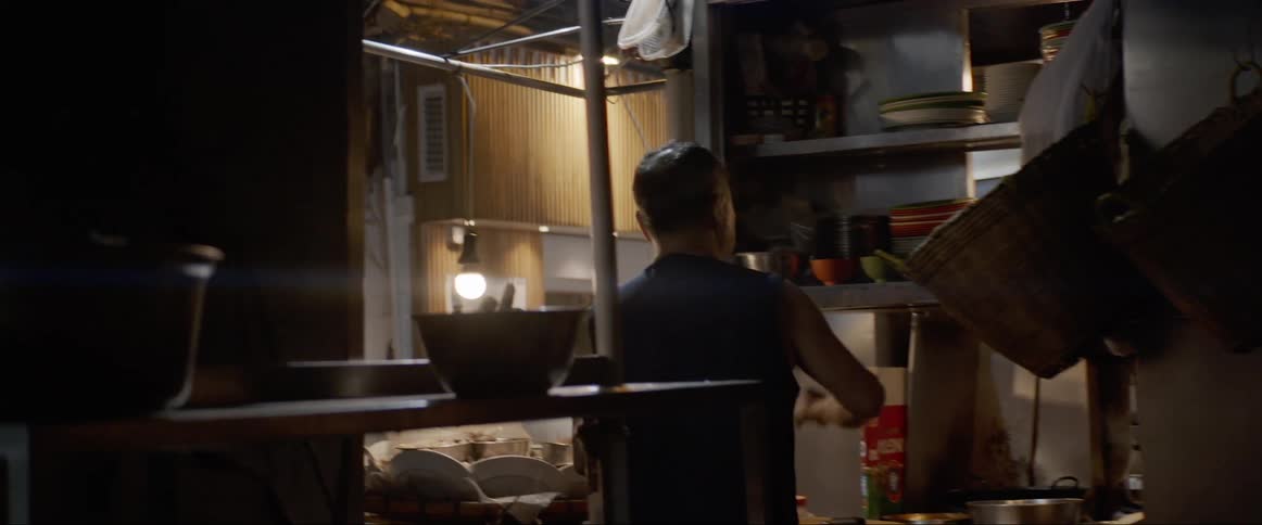 Man prepares food on a restaurant in a market at night