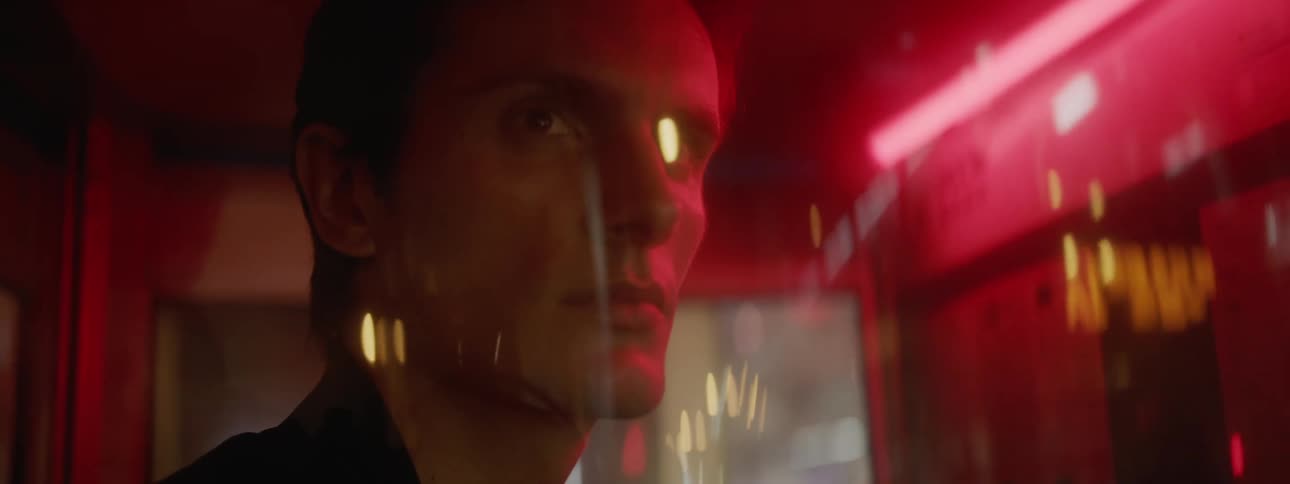 A man looks out the train windows as he travels past city buildings at night