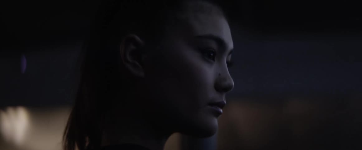 An asian woman walks indoors while casting a thoughtful glance to her side