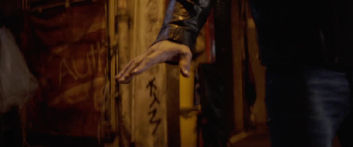 Man wearing leather jacket turns around in an alleway
