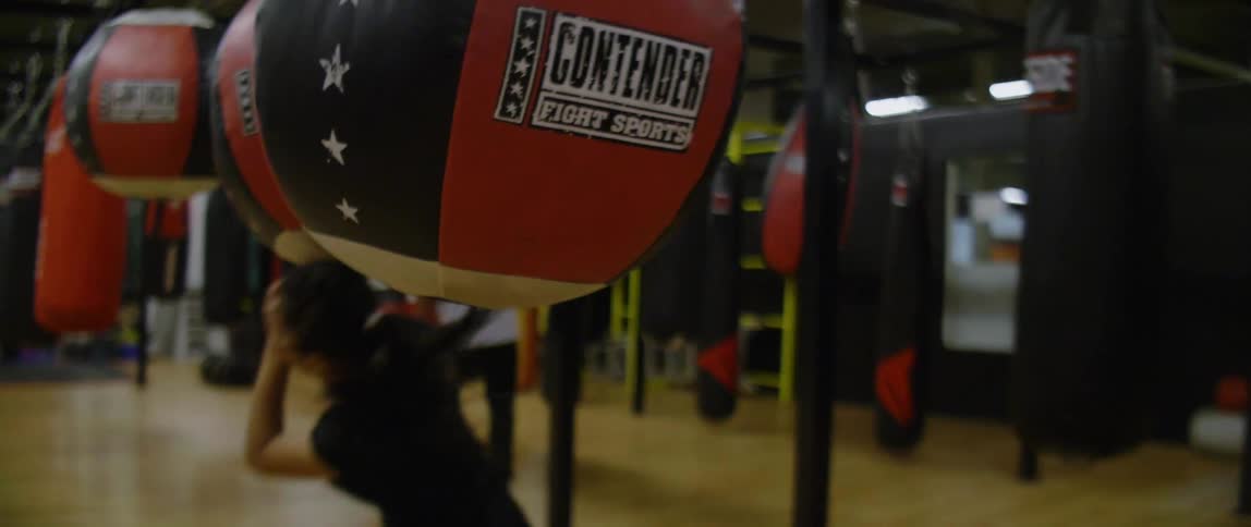 Woman dodges punching bags as she does a fitness activity