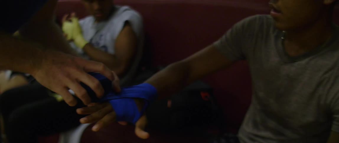 A man taping up another mans hand while a man and a woman take their hands up next to them