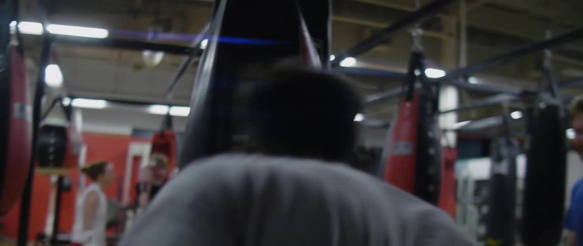 Male boxer hits the heavy bag in the gym