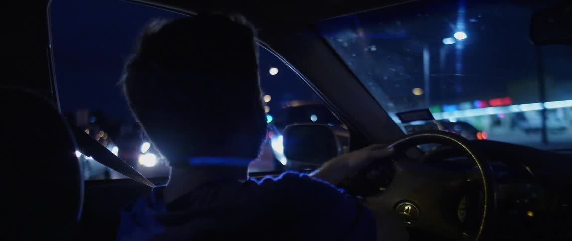 The silhouette of a man drives the car at night