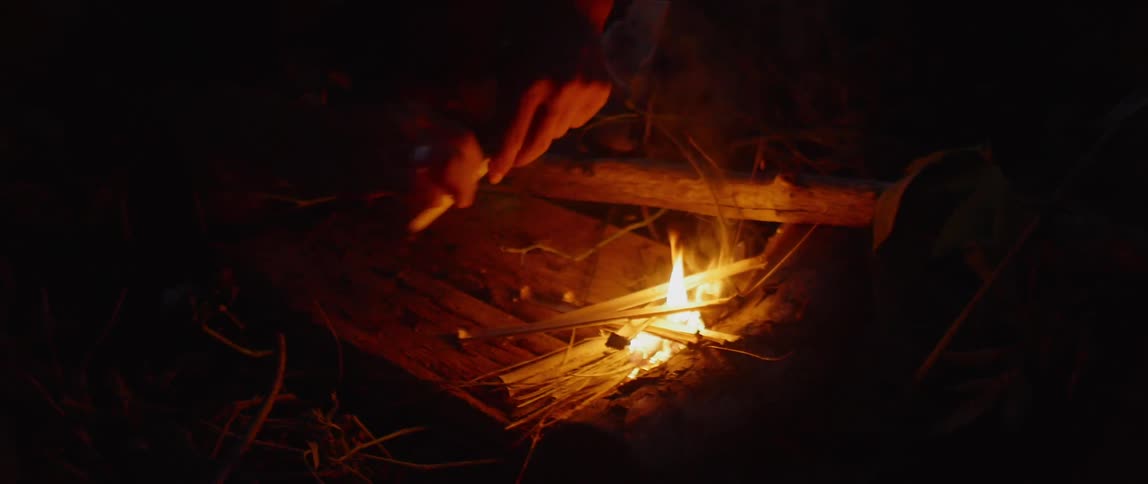 A man puts kindling on a fire