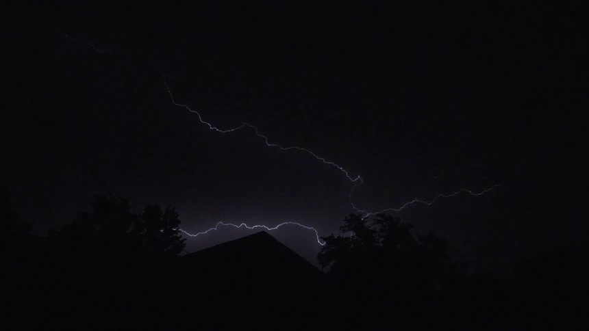 The lightning flashes behind the house