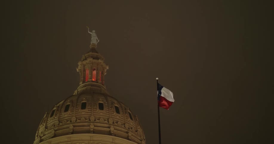 A flag flies over the capitol building of texas