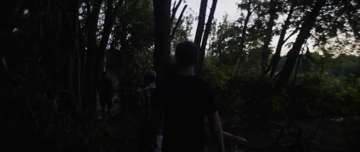 A group of teenage boys hike through dense forest