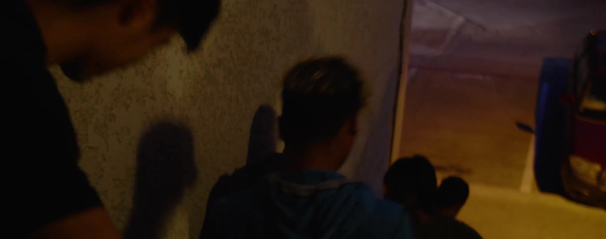 A group of teenage boys walk down a city building staircase at night