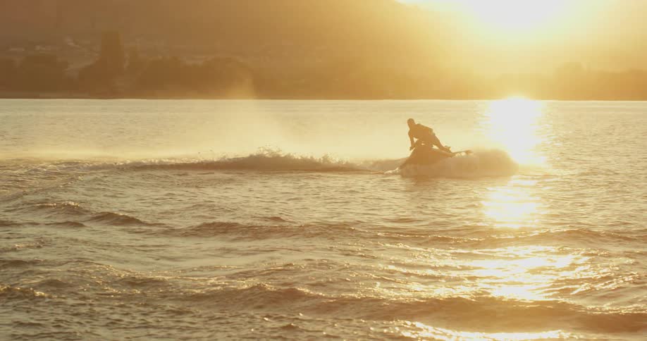 Someone drives a jet ski in the lake and creates a lot of water spray