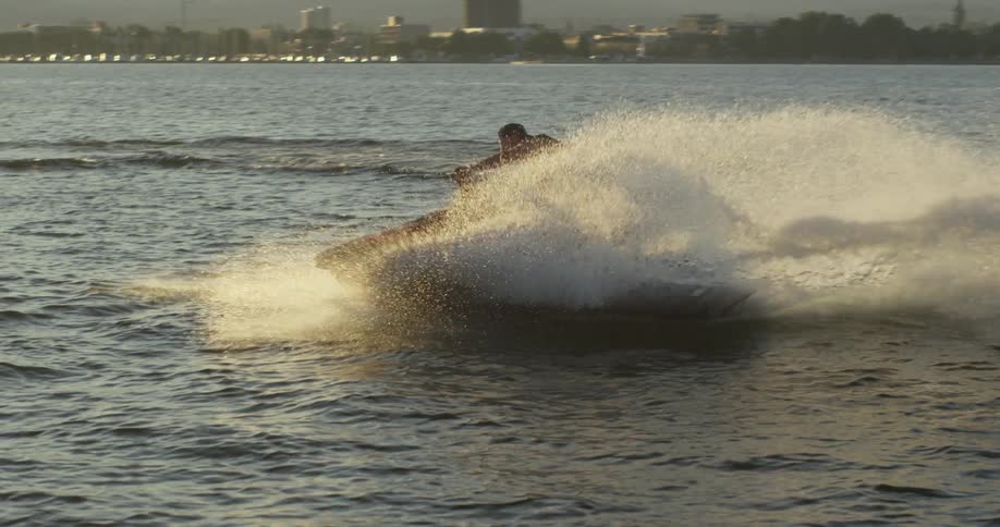 A man performing a sharp turn on a jet ski causing a wave of water to shoot into the air