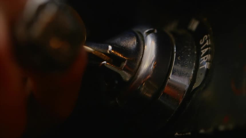 A white person turns a key in a vehicle starter