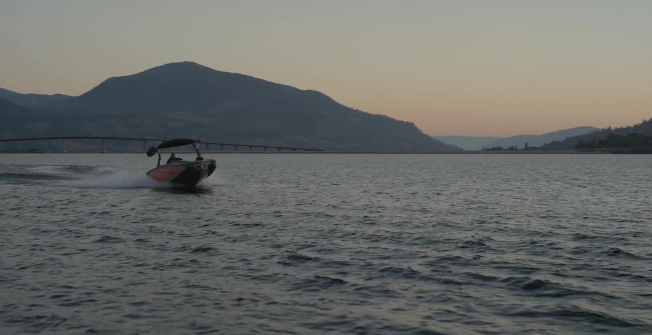 Boat speeding on a lake at sunset