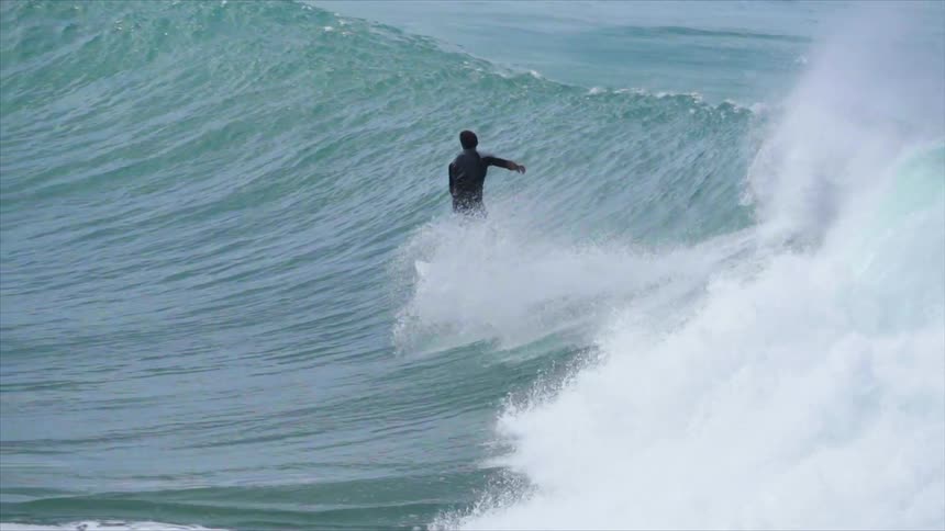 A surfer rides a cresting ocean wave