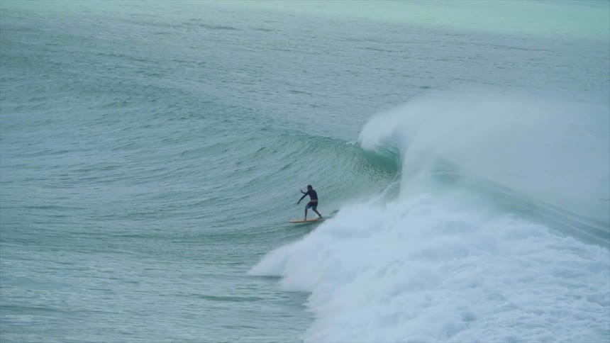 A surfer rides a breaking ocean wave