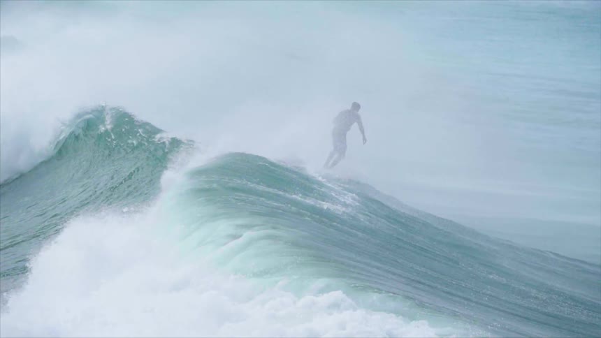 A man rides a surfboard on large ocean waves
