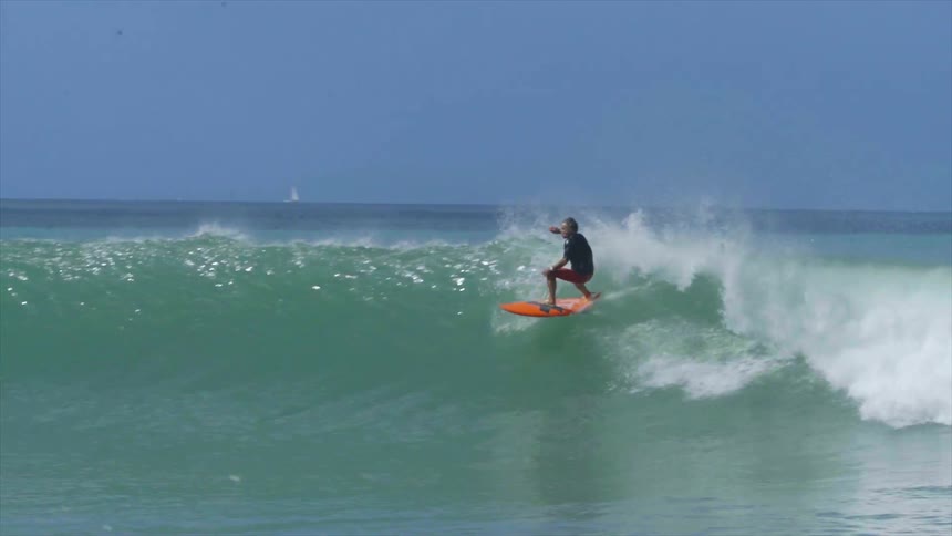 Surfer surfing small long wave on red surfboard
