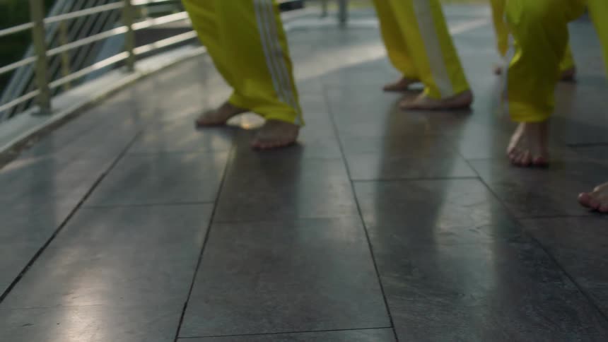 Four people dance barefoot on a tile floor