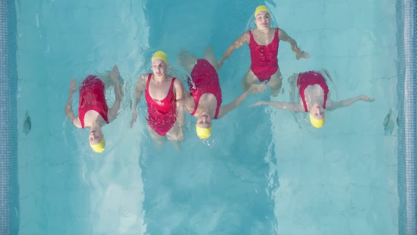 Five teenagers synchronize swim in a pool