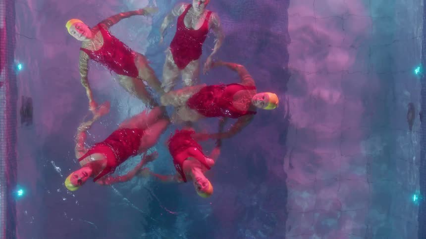 Five women swim together in an outdoor pool