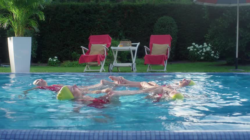 A group of female synchronized swimmers performing a routine in a pool