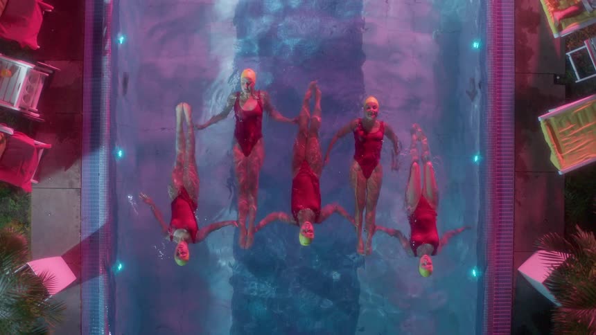 Birds eye view of five female teens synchronized swimming in a pool