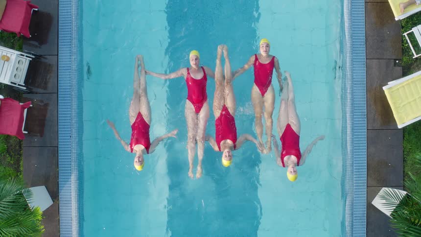 Aerial of synchronized swimmers floating in a backyard pool