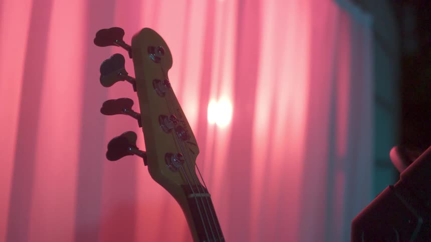 Four keys attached to a stringed instrument sits near the red curtains