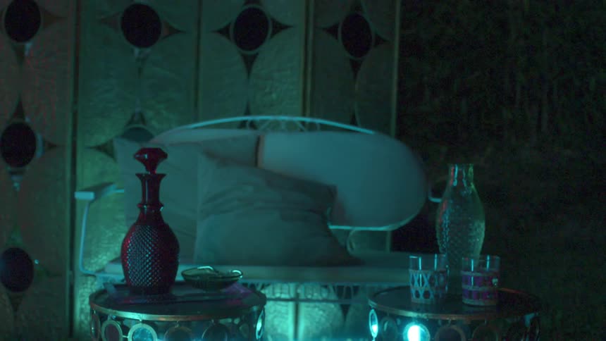 Furniture with bottles and glasses outdoors at night