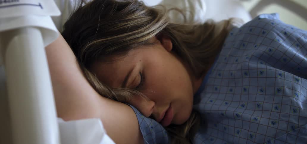 A white woman lies in bed and sleeps