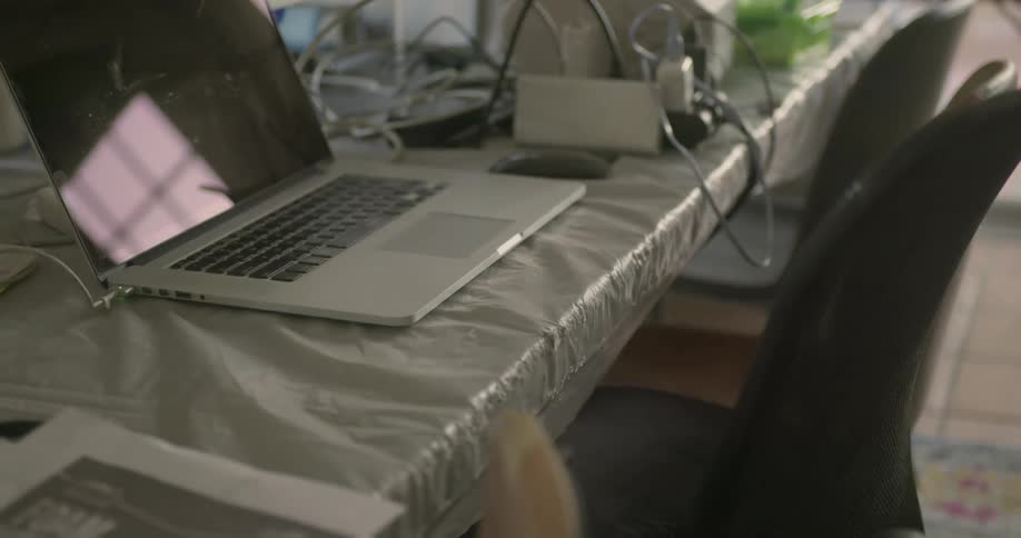A laptop sits open on a desk with a chair