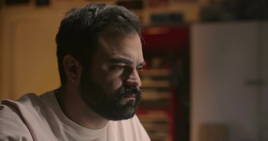 Close up of a bearded man face sitting in a dimly lit room
