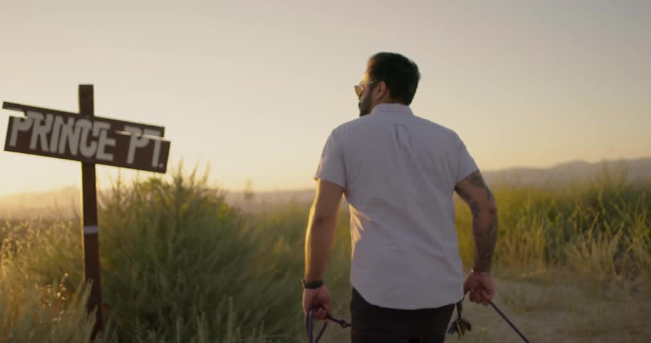 Man hiking to top of trail in the mountains with his dog