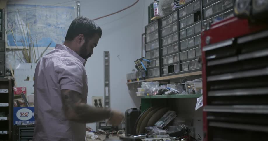 A man in a shop looks for parts in a storage area