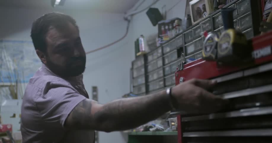 Man searches through large tool chest drawers selecting tools