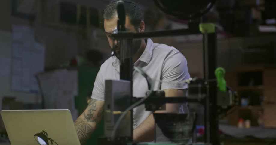 A white man uses a laptop and then checks a machine