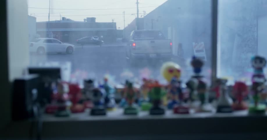 Figurines in a store window with cars driving outside in the city