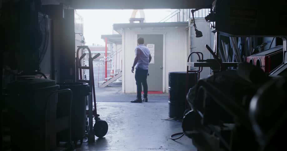 A man opens the garage door of a storage unit from the inside and steps out before closing it again