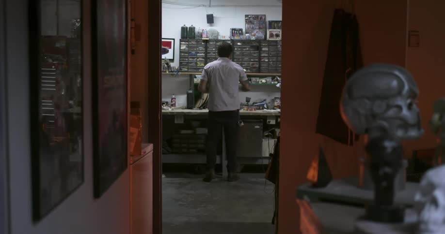 A man stands in a workshop moving around and checking various items